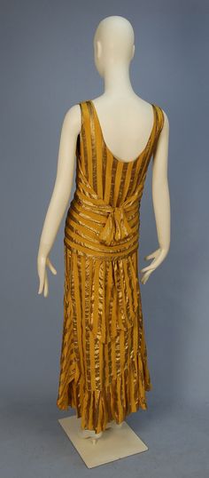 UNLABELED COUTURE SILK and LAME EVENING DRESS, 1920's. Sleeveless gold chiffon with wide gold lame stripe having over-bodice cut with deep V-back above two slits for self tie, flaring asymmetrical skirt having scalloped hem with ruffled insert and gore, chiffon under-dress. Hand sewn with couture details, probably French. Back Patches On Jeans, 1920 Dress, Historic Clothing, History Fashion, Gold Lame