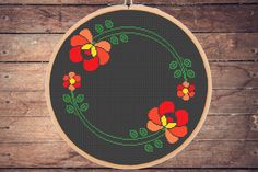 a cross stitch pattern with red and yellow flowers in a circle on a black background