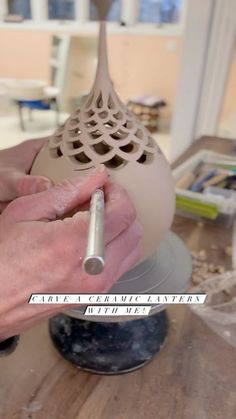 a person is working on a vase with a pen in their left hand and the other hand holding it