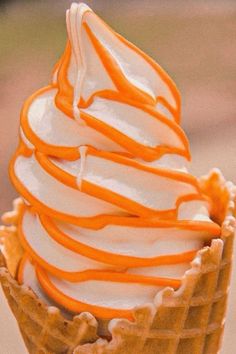 an ice cream sundae with orange swirls in a waffle cone on a table