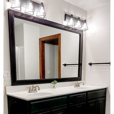 a bathroom with two sinks and a large mirror over the sink, in front of a white wall