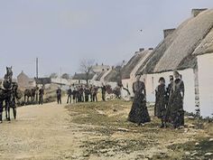 an old time photo of people and horses in front of houses with thatched roofs