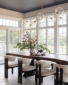 a dining room table with chairs and a vase filled with flowers