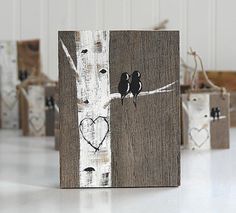 several small bags with birds on them are lined up against a white wall and one has a heart painted on it