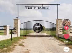 an iron gate with the words big t ranch on it in front of a grassy field