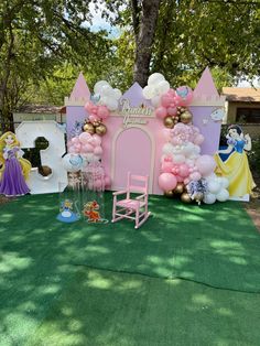 a princess themed birthday party with balloons and decorations on the lawn, including a pink castle