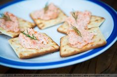 crackers with salmon on them sitting on a blue and white plate