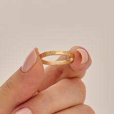 a woman's hand holding a gold ring