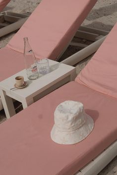 two lounge chairs and a table with a hat on it