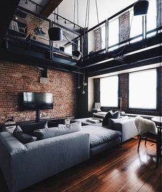 an industrial living room with exposed brick walls and wood flooring, large sectional sofa