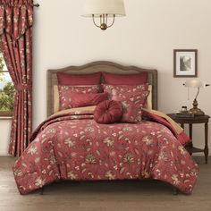 a bed in a bedroom with red and gold comforter set on it's side