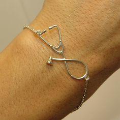 a woman's arm with a silver medical bracelet on it and a stethoscope attached to the wrist