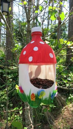 a red and white mushroom shaped bird house in the woods