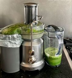 a blender sitting on top of a counter next to a container filled with green liquid