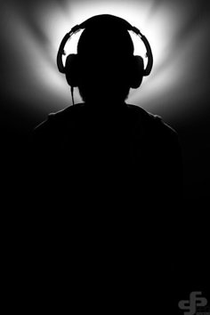 a man with headphones on in the dark, silhouetted against a bright light