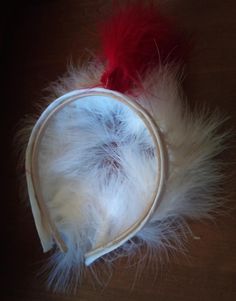 a white and red hat with feathers on the top is laying on a wooden table