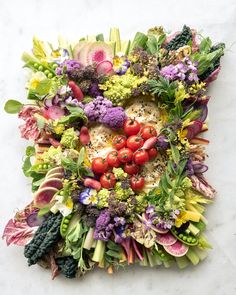 an arrangement of vegetables arranged in the shape of a square on a white surface, including tomatoes, broccoli, radishes, and other veggies