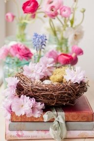 a bird's nest sitting on top of two books with flowers in the background