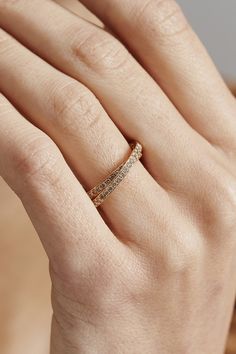 a woman's hand with a gold ring on top of her finger and the band is