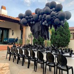 a table set up with black chairs and balloons