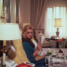 a woman sitting on a couch reading a newspaper