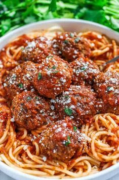 spaghetti and meatballs in a white bowl with parmesan sprinkled on top