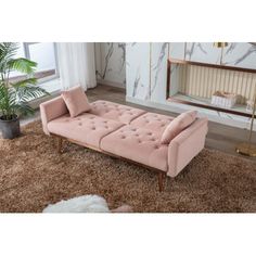 a pink couch sitting on top of a brown rug