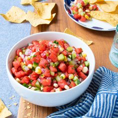 a white bowl filled with salsa next to tortilla chips and a glass of water