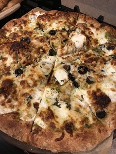 a pizza sitting on top of a pan covered in cheese and toppings next to bread