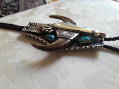 "A large Sterling silver native American turquoise large Thunderbird bolo. This artist made stunning unique bolo weighs 175.5 grams and measures 5\" long and 4\" at the widest point. The center of the thunderbird is mother of pearl (shell) and the beke is coral. The beautiful natural larger turquoise measures approx 16mm and smaller ones approx13mm. This piece is a old pawn bolo from the 50's-60's or could be earlier and is in excellent condition. The wing portion is claw. This bolo is a beautif Handmade Silver Bohemian Bolo Ties, Bohemian Silver Handmade Bolo Tie, Silver Western Bolo Ties For Festival, Handmade Southwestern Silver Bolo Ties, Silver Turquoise Western Necklace For Festivals, Native American Turquoise, American Turquoise, The Wing, Pearl Shell