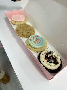 a pink box filled with cookies and frosting on top of a white countertop