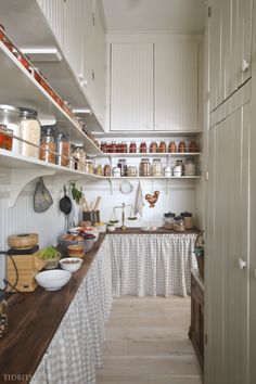 a kitchen filled with lots of white cupboards and counter top covered in pots and pans