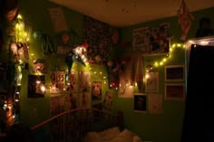 a bedroom with green walls and pictures on the wall, lights strung from the ceiling