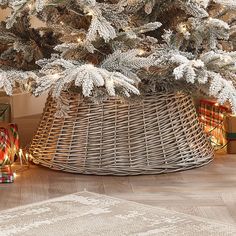 a christmas tree in a wicker basket with presents under it and lights on the floor