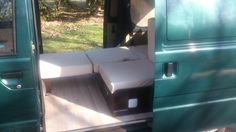 the interior of a green van with white mattresses on it's back door