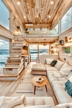 a living room filled with lots of furniture and windows next to the ocean in front of it