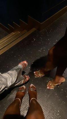 two people standing next to each other on a tiled floor with their feet in the air