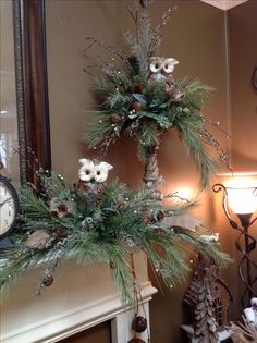 a christmas tree decorated with pine cones and white flowers in front of a fireplace mantel