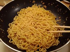 noodles being cooked in a wok with chopsticks