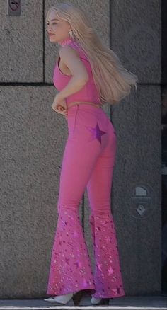 a woman with long blonde hair wearing pink pants