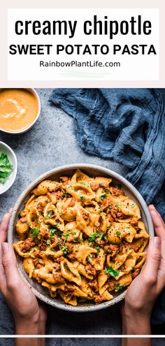 two hands holding a bowl of creamy chipotie sweet potato pasta with sauce and parsley on the side