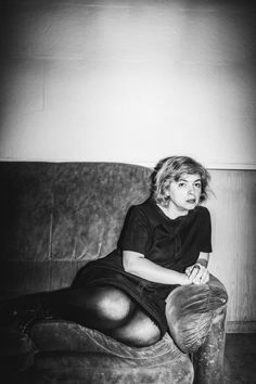 a black and white photo of a woman sitting on a couch with her legs crossed