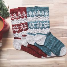 a knitted christmas stocking next to a cup of coffee on a wooden table