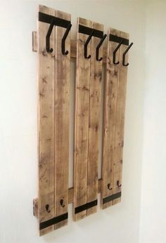 three pieces of wood are hanging on the wall with black handles and hooks attached to them