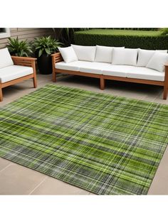 an outdoor area rug with green and white plaid pattern on it, sitting next to two couches