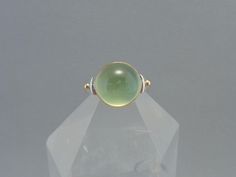 Prehnite is such an interesting stone and it really glows!! I love how it looks so mysterious...like the color of a green crystal ball. :O) This stone measures 12 mm and is set in an 18k yellow gold bezel. The balls on either side of the stone are 18k gold, as well. A fun, unusual stone ring with a great color! Prehnite is considered a gentle, nurturing stone. It is thought to help quiet nervousness and worry and can encourage a sense of peace and calm. It is associated with the heart chakra. Prehnite is found in South Africa, Namibia, Australia and China. Currently a size 7.5, I'll be happy to size this ring up or down to fit. :O) Made one at a time in my Sonoran Desert studio. xo Round Chrysoprase Opal Ring, Round Opal Chrysoprase Ring, Green Oval Prehnite Rings, Green Cabochon Dome Ring For Formal Occasions, Unique Green Gemstones For Formal Occasions, Elegant Green Cabochon Moonstone Ring, Green Cabochon Moonstone Ring Gift, Green Cabochon Moonstone Ring, Green Prehnite Round Jewelry