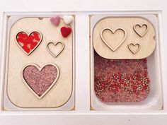 two wooden containers filled with different types of food and hearts on the top one has red, white and pink sprinkles in them