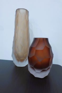 two vases sitting on top of a table next to each other, one brown and one white