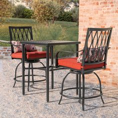 a patio table with two chairs and an orange cushion on it next to a brick wall