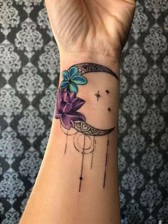 a woman's wrist with a flower on it and the moon in the background